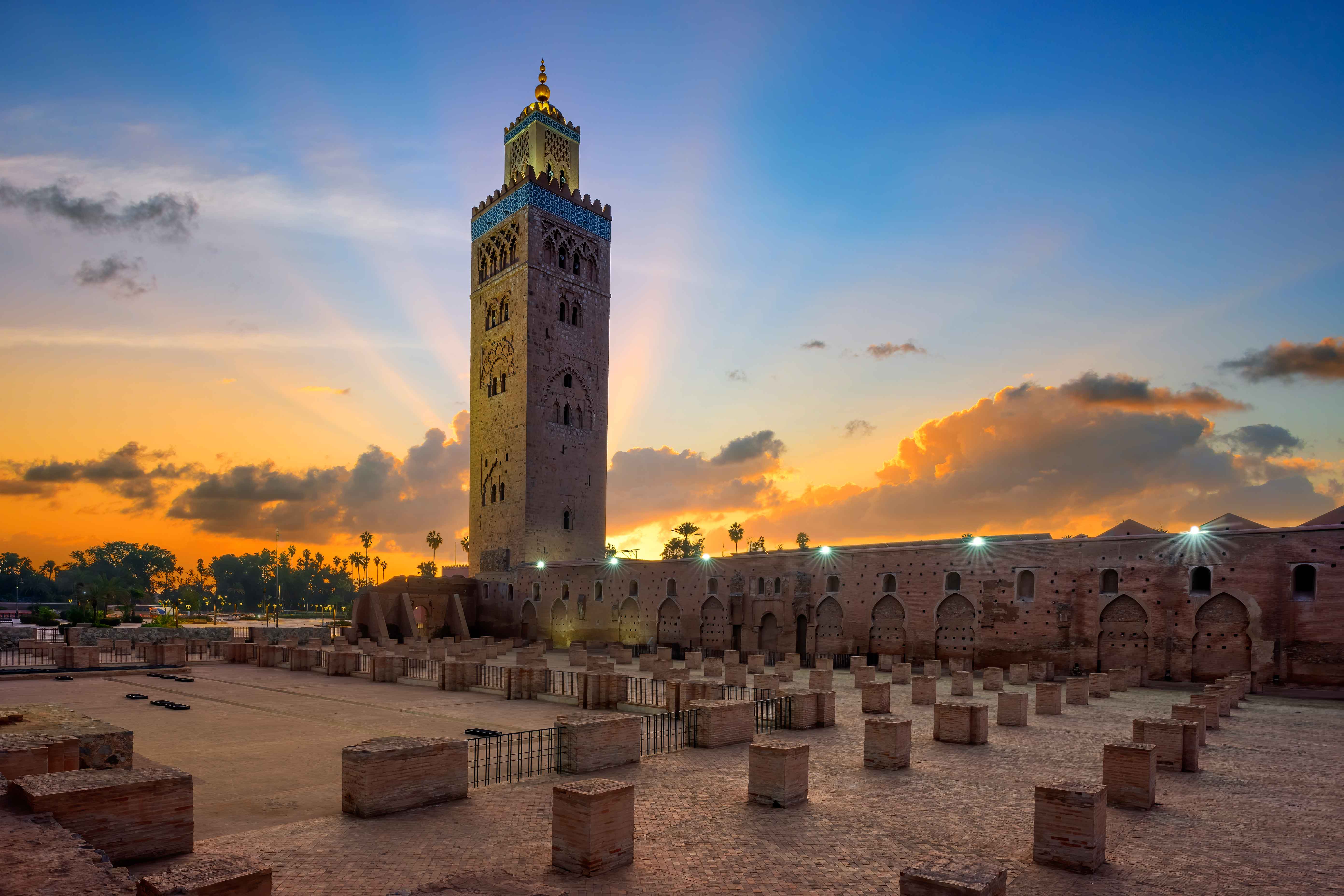 Koutoubia Mosque in Marrakech, Morocco, illuminated at sunset with its iconic minaret and vibrant city skyline.