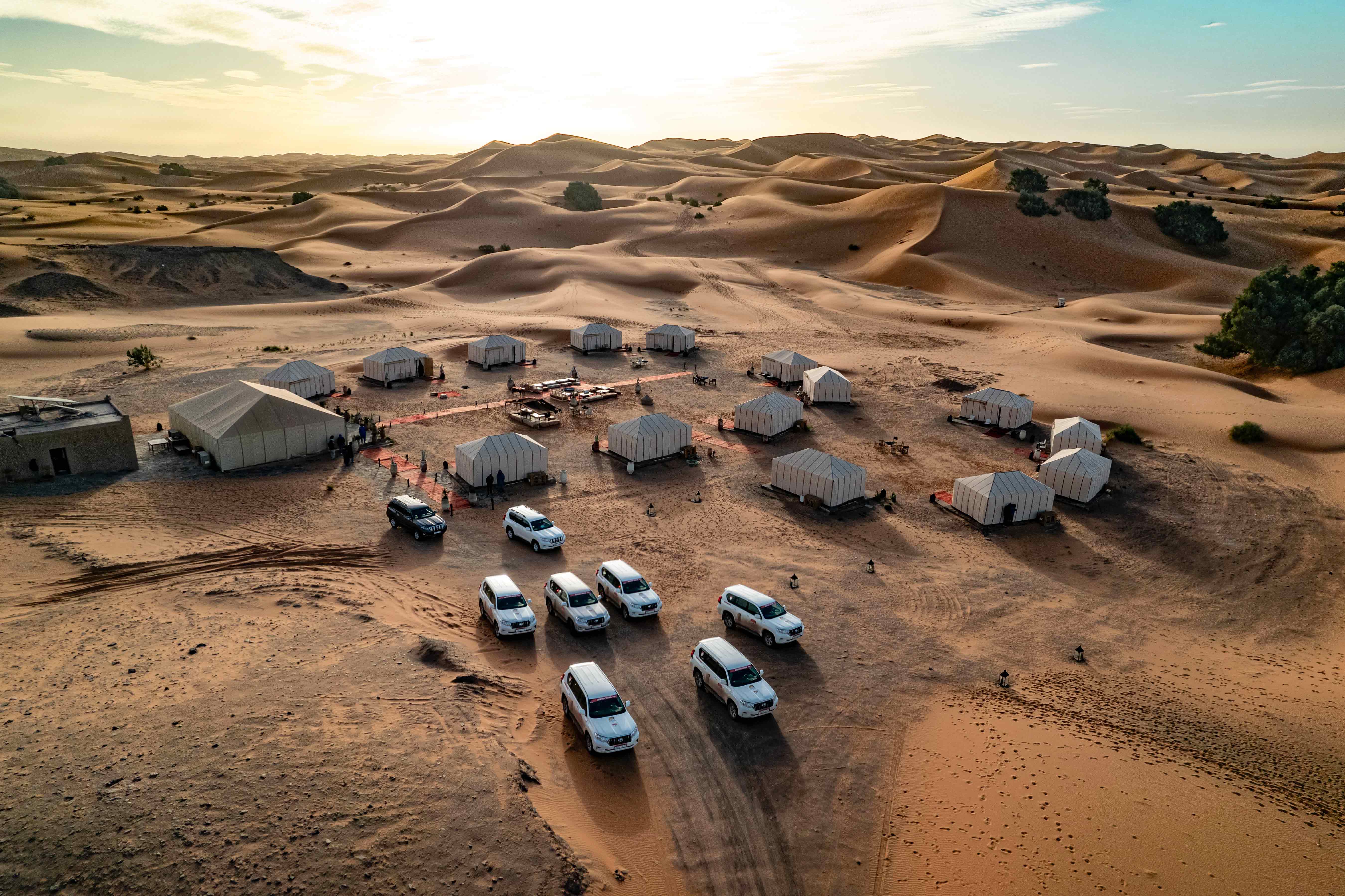 Luxury desert camp with 4x4 vehicles in the Sahara Desert, Morocco, offering an unforgettable glamping and off-road adventure experience.