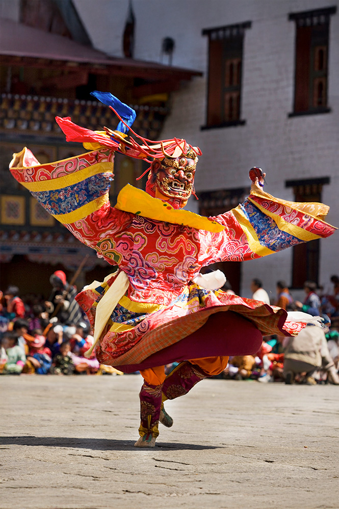 Traditional masked dancer performing at a vibrant Bhutanese cultural festival.