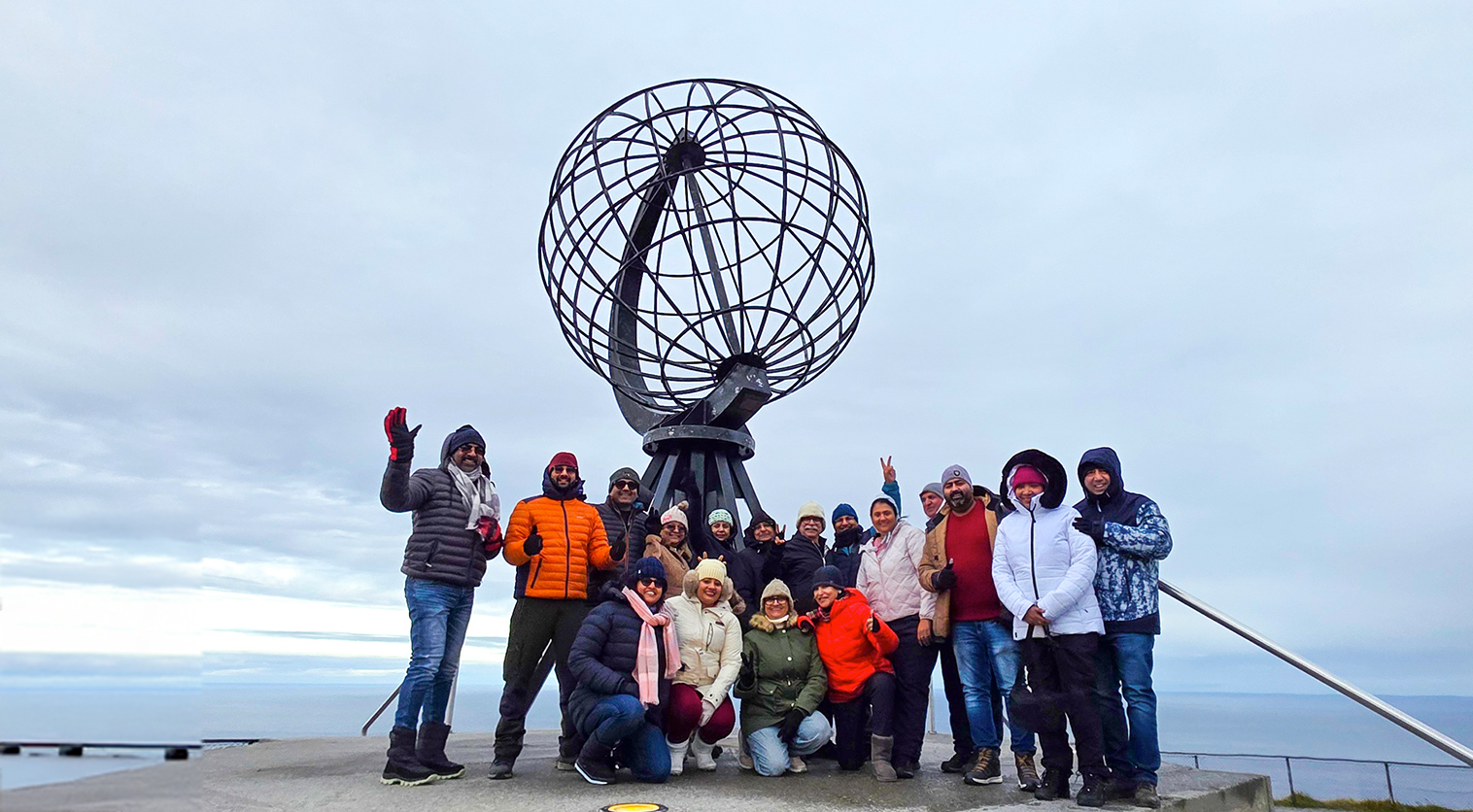 Travel group at the iconic North Cape Globe Monument in Norway.